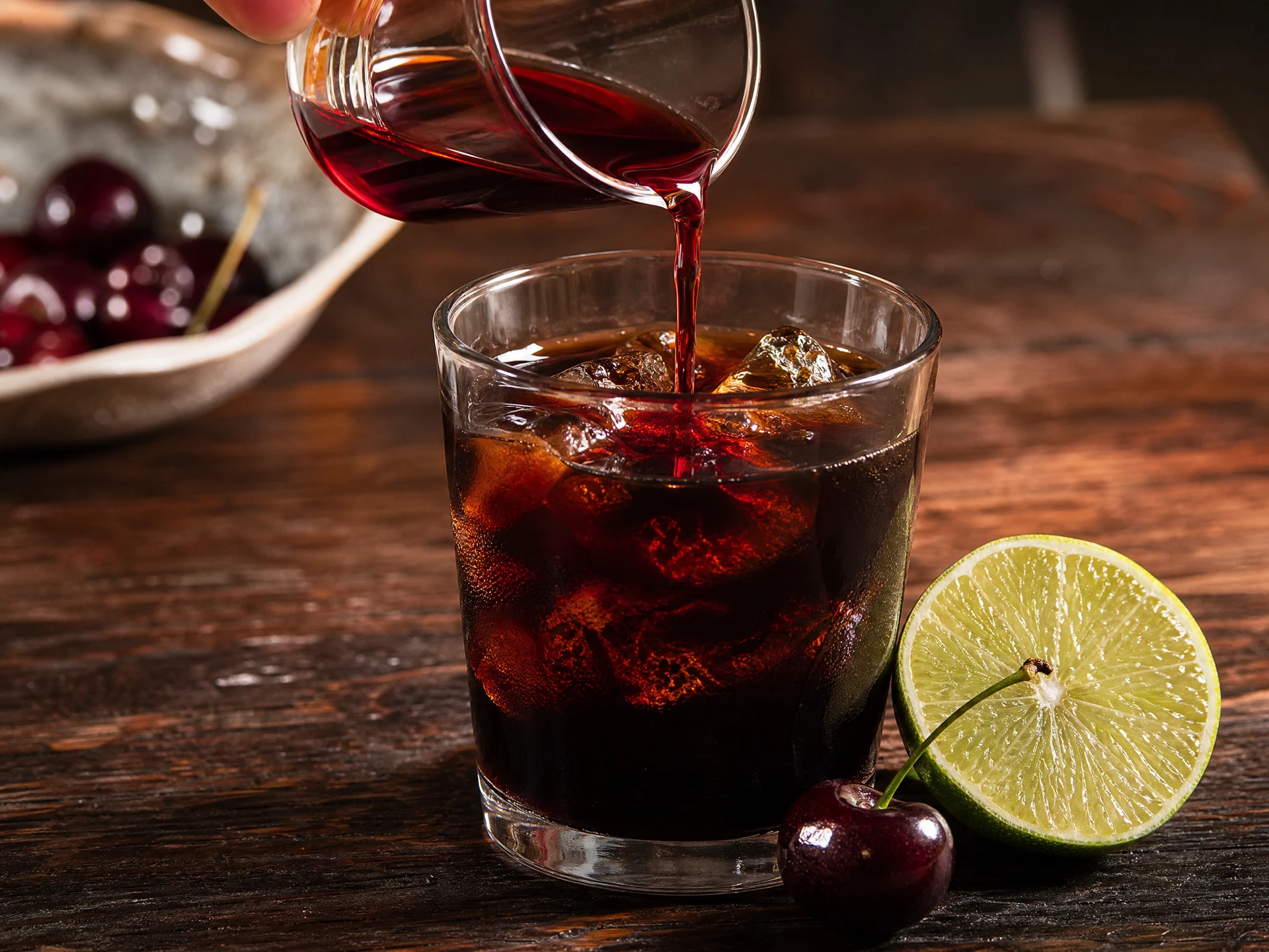 A close-up view of the bubbles rising through a layered Cherry Cola Cold Brew, showing the contrast between the dark coffee and the vibrant cherry juice.