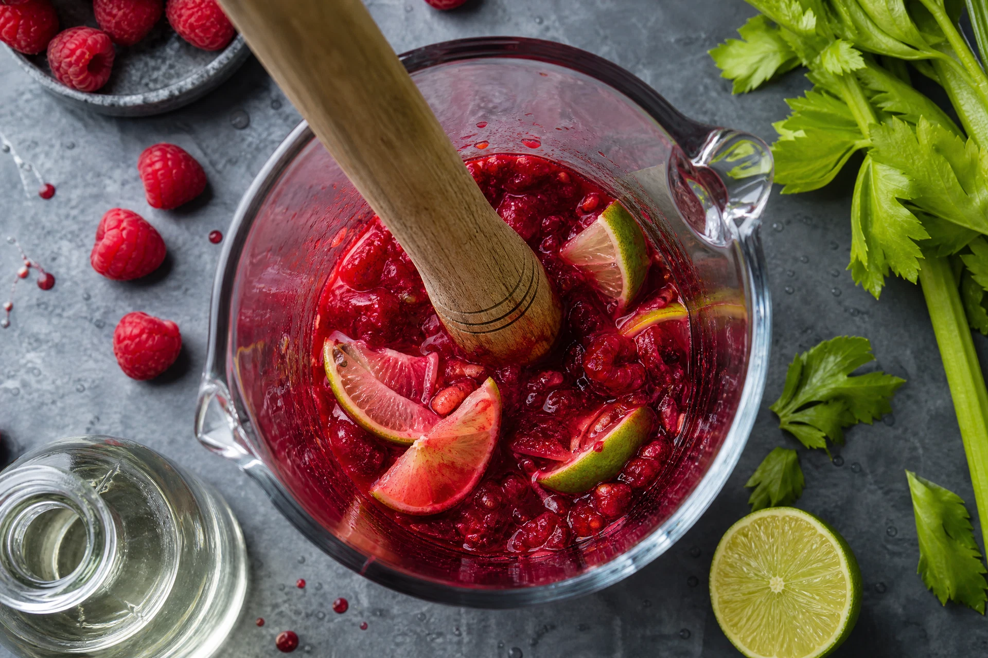 Close-up of muddled raspberries and lime juice being prepared for a zero-proof drink.