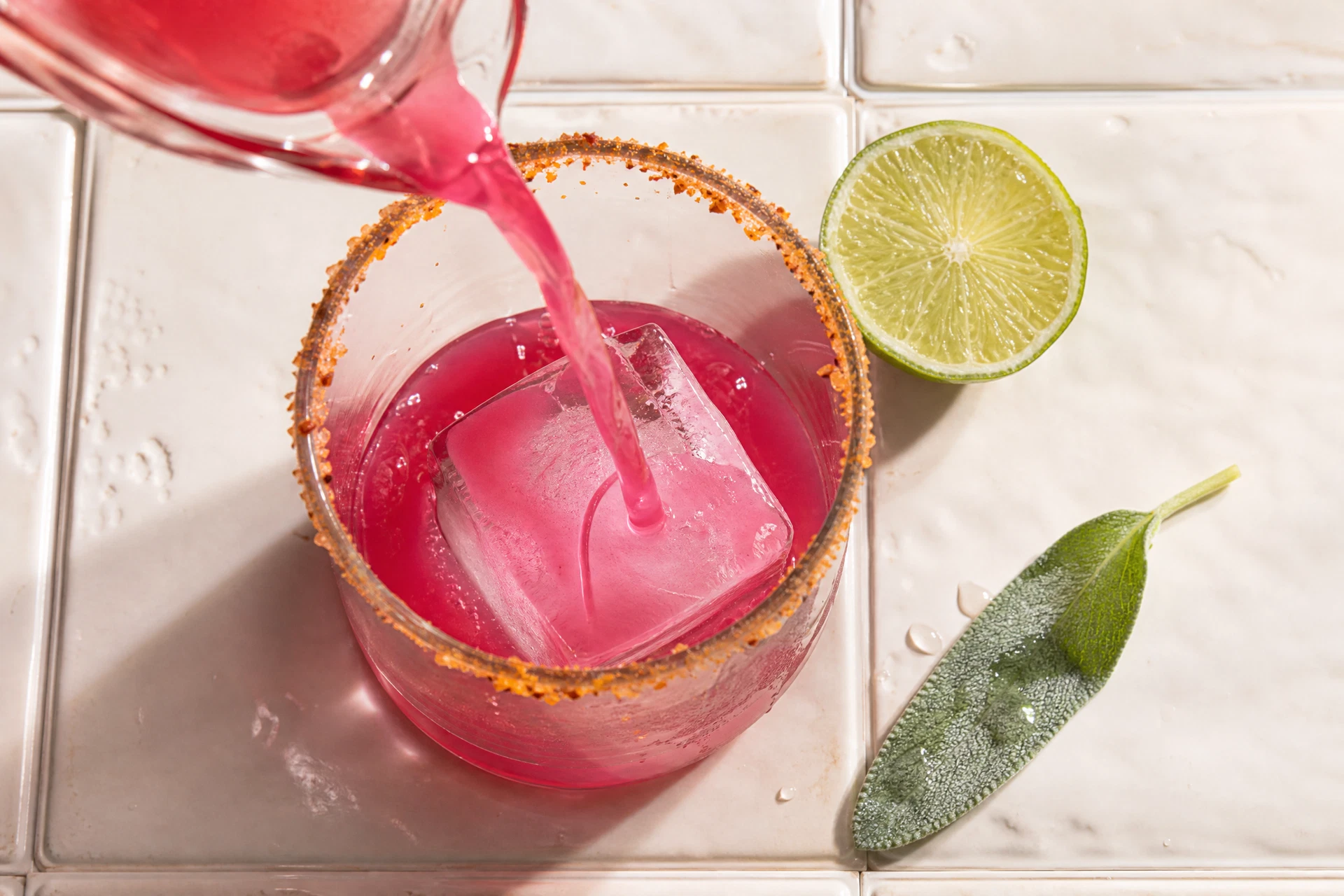 Close-up of fresh sage leaves being muddled with lime juice for a desert-inspired drink.