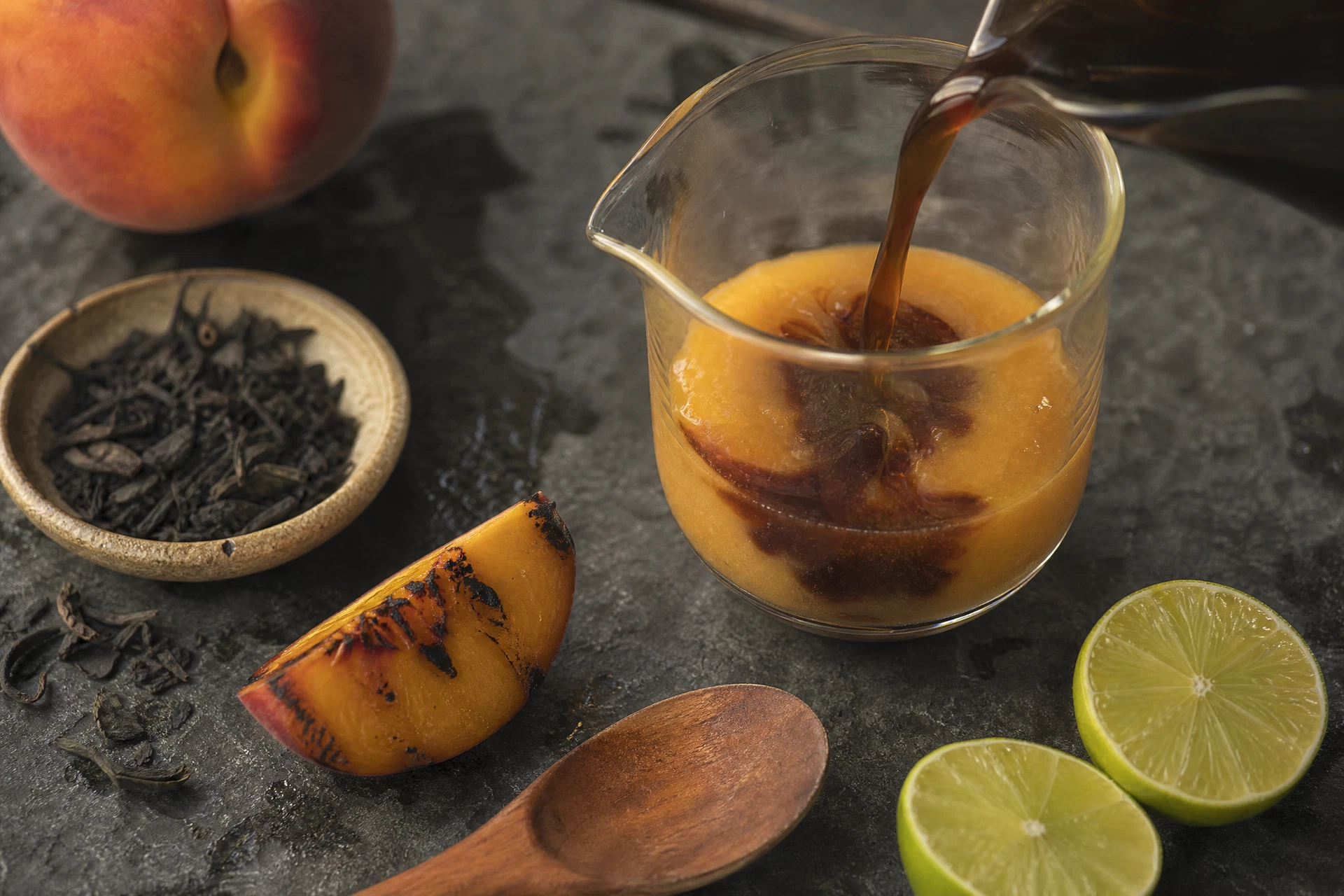 Close up of tamarind concentrate being stirred into a peach and tea base.
